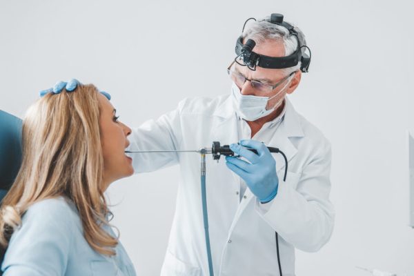 Doctor otolaryngologist making endoscopic examination of oral cavity for female patient at office
