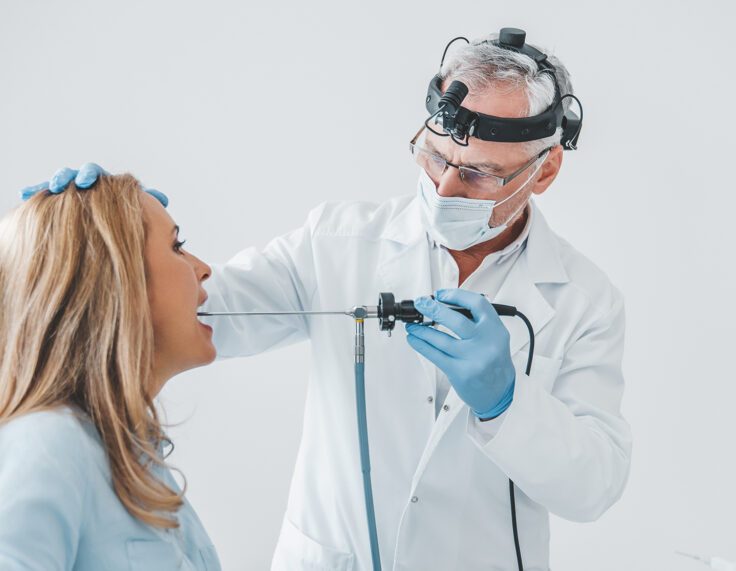 Doctor otolaryngologist making endoscopic examination of oral cavity for female patient at office